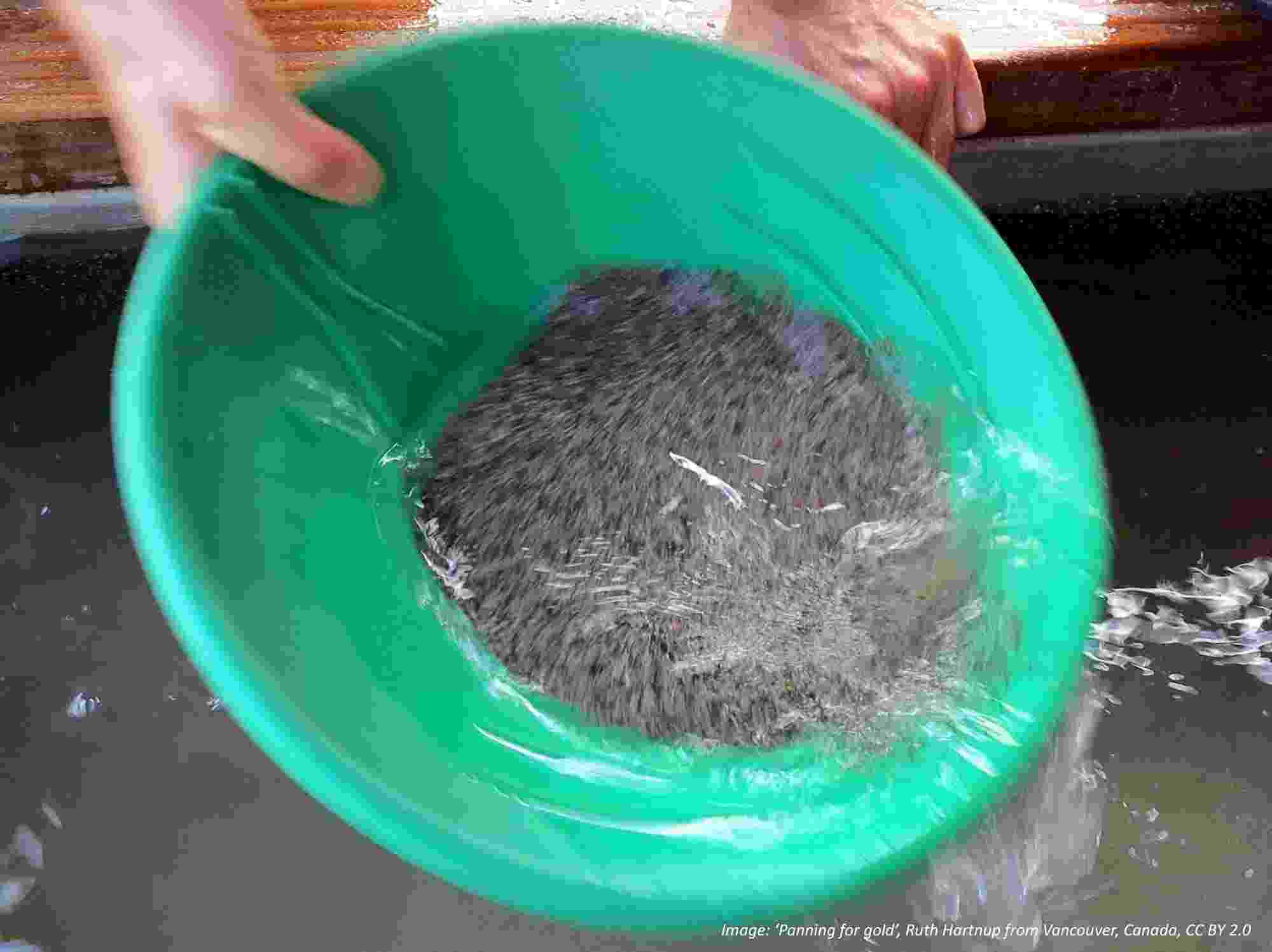 Top down view of a green bowl being used to pan for gold